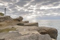 the ocean is calm as if it's on a rocky cliff beside the lighthouse