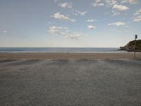 the empty parking lot near the ocean under a cloudy blue sky is surrounded by gray stones