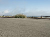 a person riding a bike on the beach side with fog rising from behind them and hills in the distance