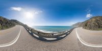 a 360 - view of the ocean on a road with a fence in front of it