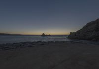 a view of the ocean from an overlook at sunset time with rocks in the foreground