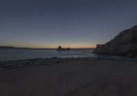 a view of the ocean from an overlook at sunset time with rocks in the foreground