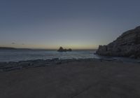 a view of the ocean from an overlook at sunset time with rocks in the foreground