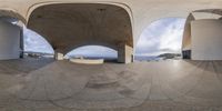 view from inside an arch looking at an ocean with benches and tables in it that appear to be full size