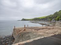 a walkway next to the ocean with a small boat parked in it on rocks and dirt