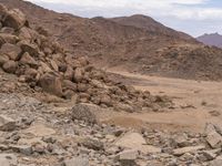 two people riding on horses in the desert with large rocks and boulders in the background