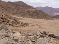 two people riding on horses in the desert with large rocks and boulders in the background