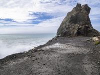 waves crashing on the shoreline with rocks and rock formations on a beach next to the water