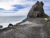 waves crashing on the shoreline with rocks and rock formations on a beach next to the water