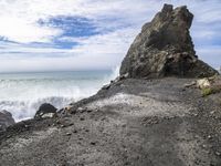 waves crashing on the shoreline with rocks and rock formations on a beach next to the water