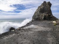 waves crashing on the shoreline with rocks and rock formations on a beach next to the water