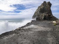 waves crashing on the shoreline with rocks and rock formations on a beach next to the water