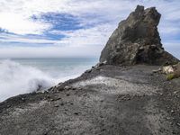 waves crashing on the shoreline with rocks and rock formations on a beach next to the water