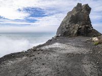 waves crashing on the shoreline with rocks and rock formations on a beach next to the water