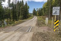 a dirt road with trees and a sign indicating to be careful of the distance between two sections