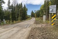 a dirt road with trees and a sign indicating to be careful of the distance between two sections