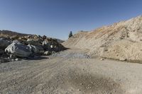 there is a bike rider on a paved dirt road through rocky area near a mountain