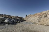 there is a bike rider on a paved dirt road through rocky area near a mountain