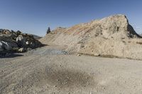 there is a bike rider on a paved dirt road through rocky area near a mountain