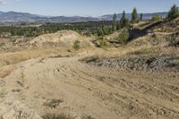 there is a bike rider on a paved dirt road through rocky area near a mountain