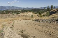 there is a bike rider on a paved dirt road through rocky area near a mountain