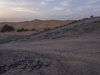 a truck on a dirt road in the desert with rocks and stones on the ground