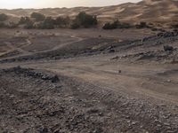 a truck on a dirt road in the desert with rocks and stones on the ground