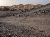 a truck on a dirt road in the desert with rocks and stones on the ground