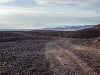 gravel road leading to distant mountains with clouds in the sky on a cloudy day,