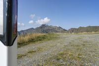 a motorcycle parked on a small mountain side road near mountains with no cars driving on it