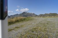 a motorcycle parked on a small mountain side road near mountains with no cars driving on it