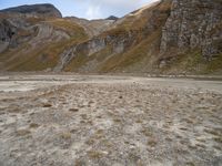 mountains with many rock formations in the foreground and a sparse grassy field with small grass