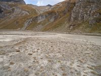 mountains with many rock formations in the foreground and a sparse grassy field with small grass