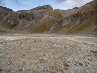 mountains with many rock formations in the foreground and a sparse grassy field with small grass