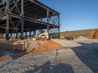 a picture of a building being built on a field near a forest in the background