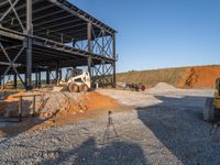 a picture of a building being built on a field near a forest in the background