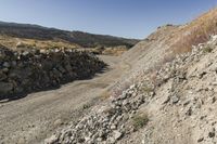 there is a bike rider on a paved dirt road through rocky area near a mountain