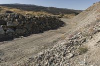 there is a bike rider on a paved dirt road through rocky area near a mountain