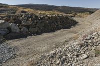 there is a bike rider on a paved dirt road through rocky area near a mountain