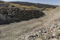 there is a bike rider on a paved dirt road through rocky area near a mountain