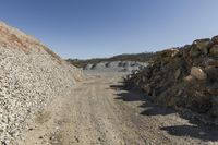 there is a bike rider on a paved dirt road through rocky area near a mountain