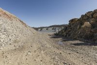 there is a bike rider on a paved dirt road through rocky area near a mountain