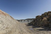 there is a bike rider on a paved dirt road through rocky area near a mountain