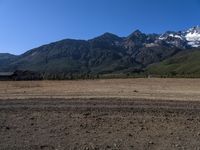 a lone horse stands in an open plain with mountains in the distance in this file