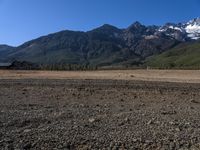 a lone horse stands in an open plain with mountains in the distance in this file