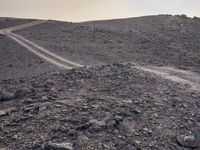 a truck on a dirt road in the desert with rocks and stones on the ground