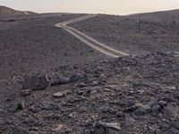 a truck on a dirt road in the desert with rocks and stones on the ground