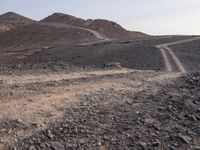 a truck on a dirt road in the desert with rocks and stones on the ground