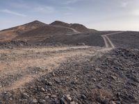 a truck on a dirt road in the desert with rocks and stones on the ground