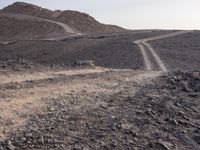 a truck on a dirt road in the desert with rocks and stones on the ground